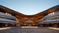 The curved roof integrates with a woven, timber structure, welcoming patrons to the Bunjil Palace multipurpose arts, civic and community facility in Narre Warren, Australia. The curved roof integrates with a woven, timber structure, welcoming patrons to the Bunjil Palace multipurpose arts, civic and community facility in Narre Warren, Australia.