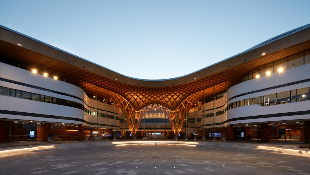 The curved roof integrates with a woven, timber structure, welcoming patrons to the Bunjil Palace multipurpose arts, civic and community facility in Narre Warren, Australia.