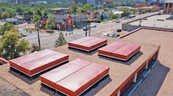 Roofers installed four acoustical smoke vents from BILCO. The 5 &times; 7 ft. vents include burglar bars to prevent unauthorized entry and a manual winch. Given the high school&rsquo;s location downtown, acoustical smoke vents help limit noise intrusion from exterior sources.