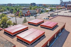 Roofers installed four acoustical smoke vents from BILCO. The 5 &times; 7 ft. vents include burglar bars to prevent unauthorized entry and a manual winch. Given the high school&rsquo;s location downtown, acoustical smoke vents help limit noise intrusion from exterior sources.