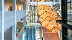 Running alongside an escalator on one side and an expansive curtain wall on the other is the Pacific Madrone wooden Hill Climb with blackened steel railings.