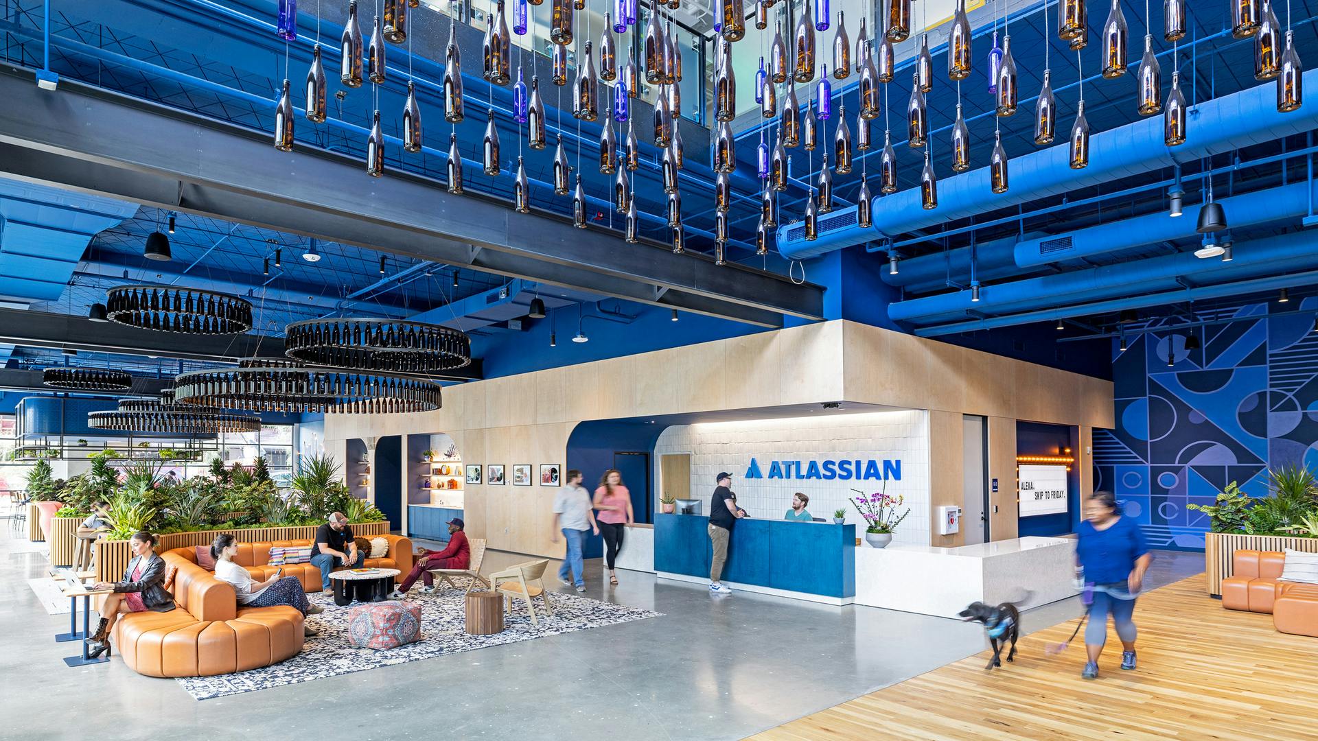 Next to the reception desk is a coffee shop with leather sofa seating. The bottle installation (foreground) and the bottle chandeliers were designed by the Mithun team and crafted by local maker Sarabi Studio.