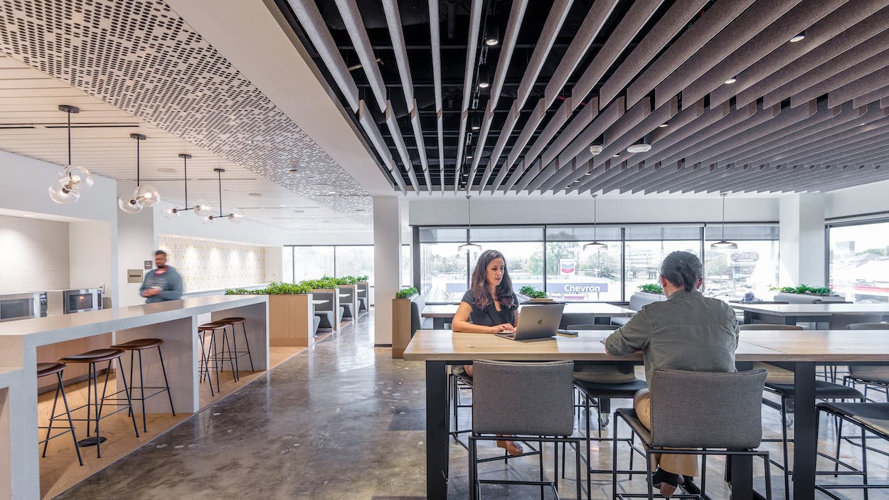 The company caf&eacute; features decorative pendant lighting from E. Kraemer over the bar tables and Tech Lighting over the booths. Track lighting is recessed within the ceiling baffles.