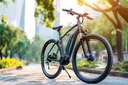 AI rendering of black e-bike with blurred park and cityscape in background. AI rendering of black e-bike with blurred park and cityscape in background.