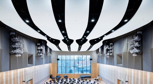 Interior of John Barry Performance Hall showing close-up of glass fiber reinforced acoustic panels in the ceiling and the student chairs and window.