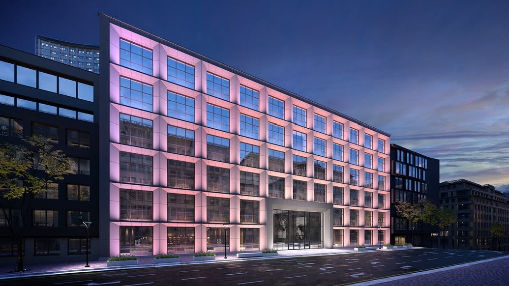Building facade with exterior lights in soft purples, pinks, yellows, and white.