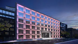 Building facade with exterior lights in soft purples, pinks, yellows, and white.