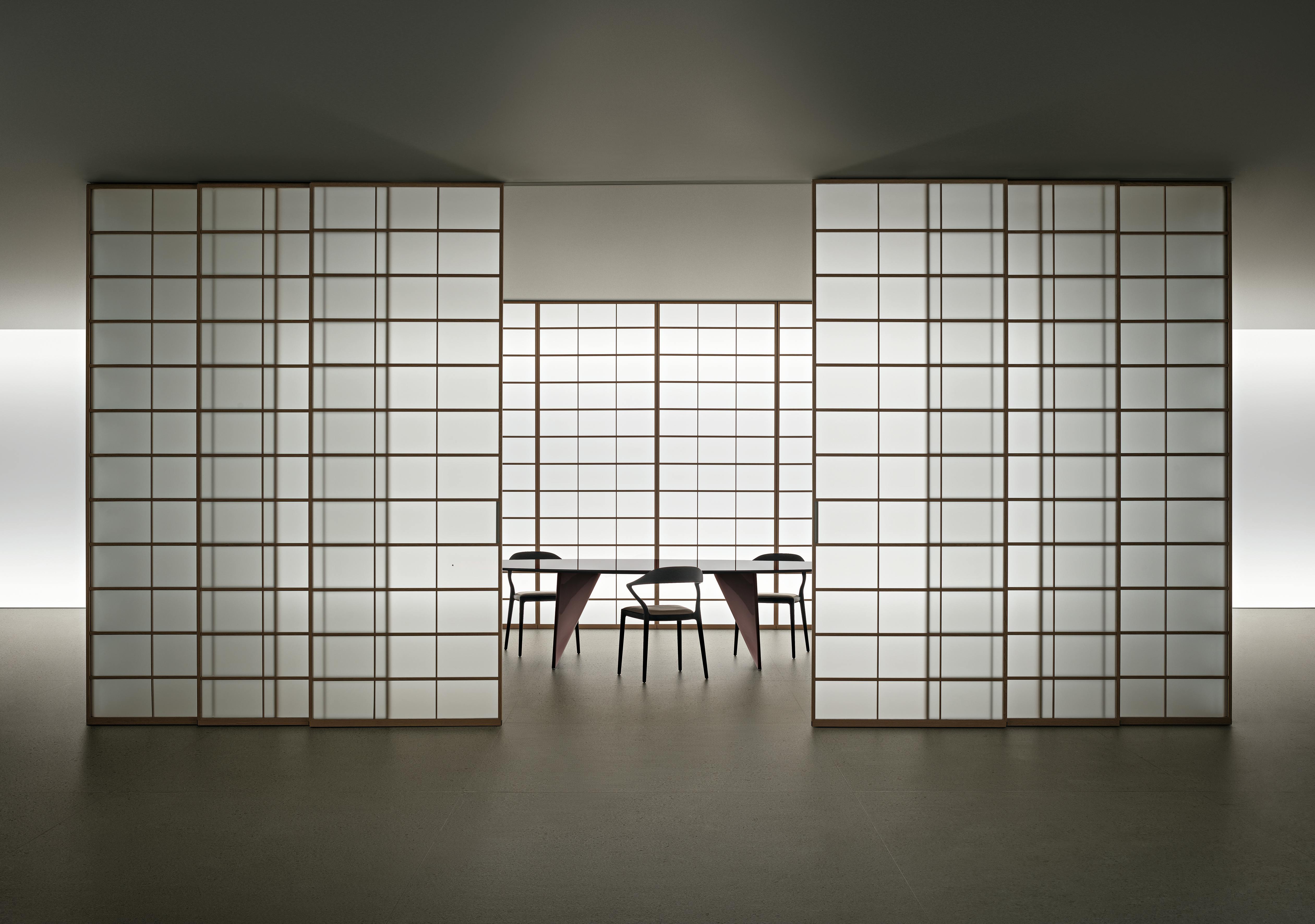 Sliding door system made from translucent panels with gridded aluminum pattern reveal partial view of conference table and chairs inside the room.