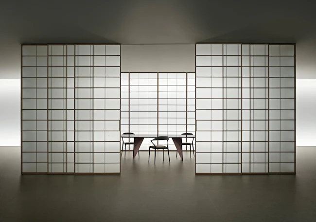 Sliding door system made from translucent panels with gridded aluminum pattern reveal partial view of conference table and chairs inside the room.