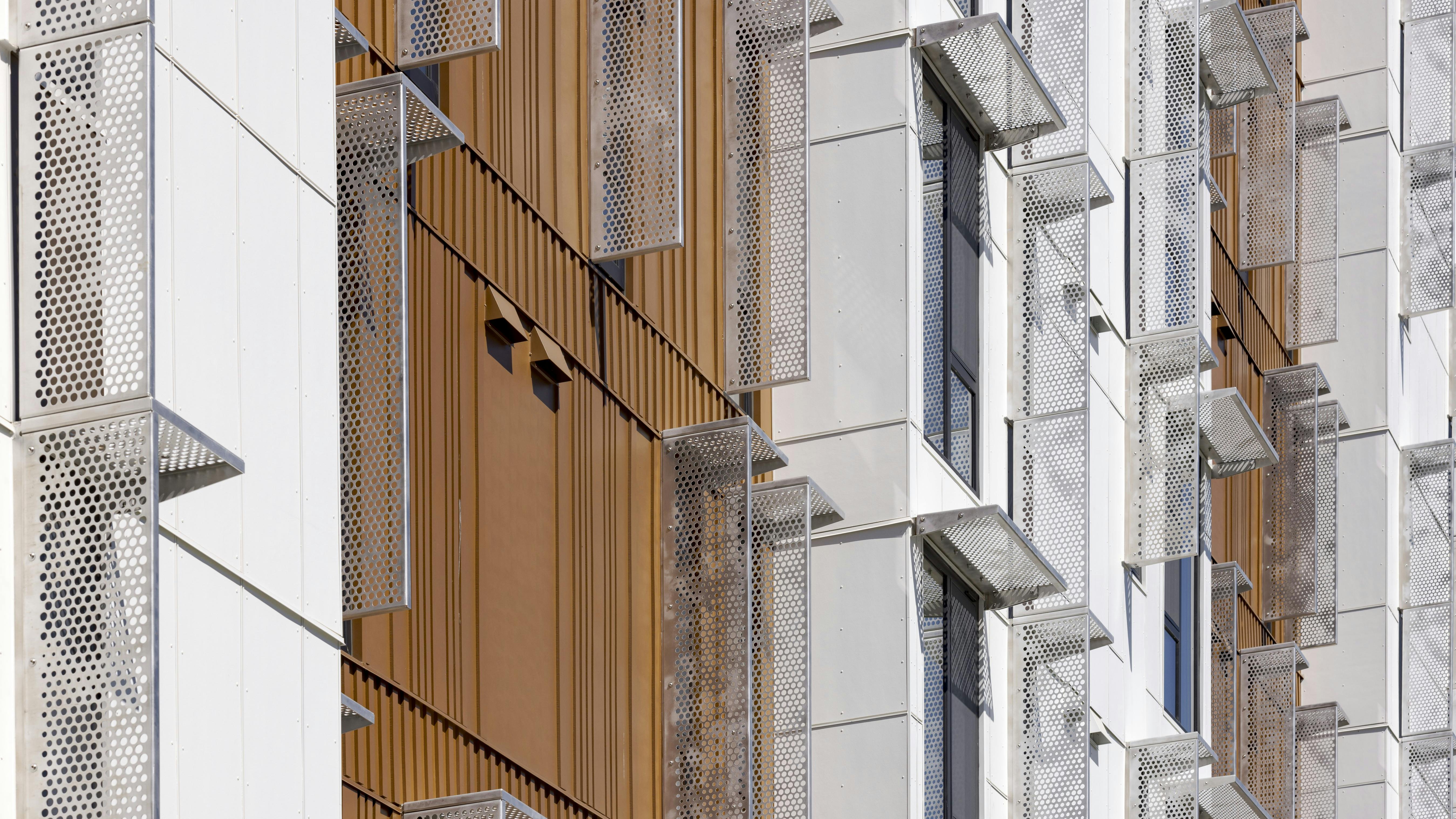 Building exterior with rust-look metal facade and bracketless solar shades.