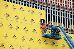 Installation of DensGlass Sheathing, rows of gold-finished fiberglass mats on structural frame.