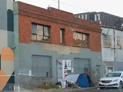 Original brick facade with broken windows, partially painted, etc.