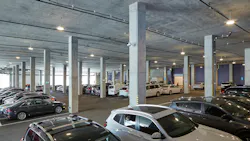 Interior of a parking garage showing cars, concrete beams, and SensScape SPG18 parking luminaires.