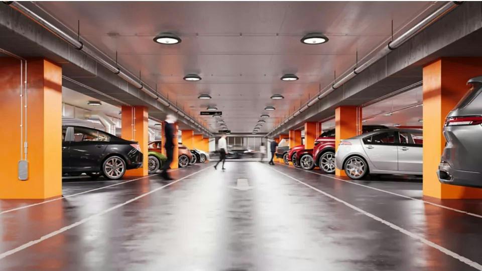 Parking garage with orange columns, gray polished floor, and TopTier Visual Comfort luminaires.