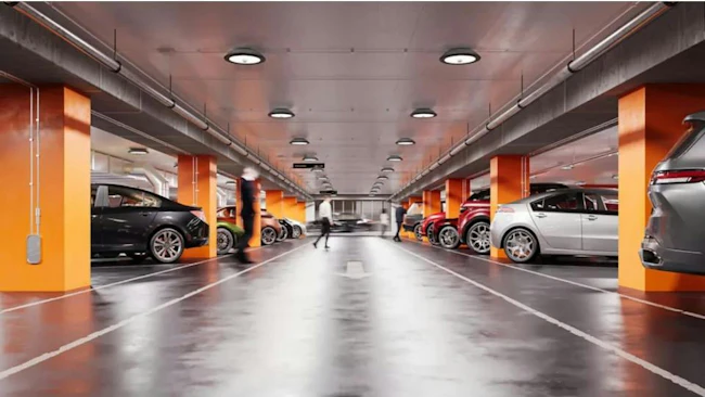 Parking garage with orange columns, gray polished floor, and TopTier Visual Comfort luminaires.
