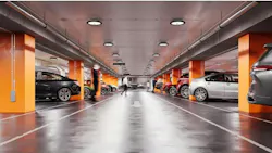 Parking garage with orange columns, gray polished floor, and TopTier Visual Comfort luminaires.