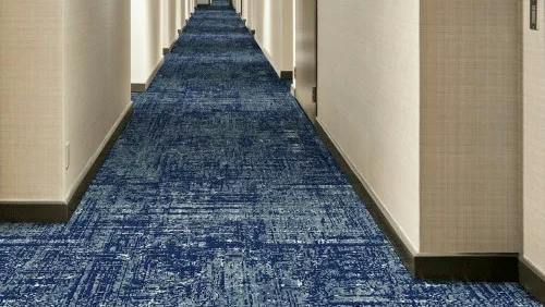 Broadloom carpet in a mixture of blue swirls, named Tide, installed down a hallway in a hospitality venue.