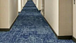 Broadloom carpet in a mixture of blue swirls, named Tide, installed down a hallway in a hospitality venue.